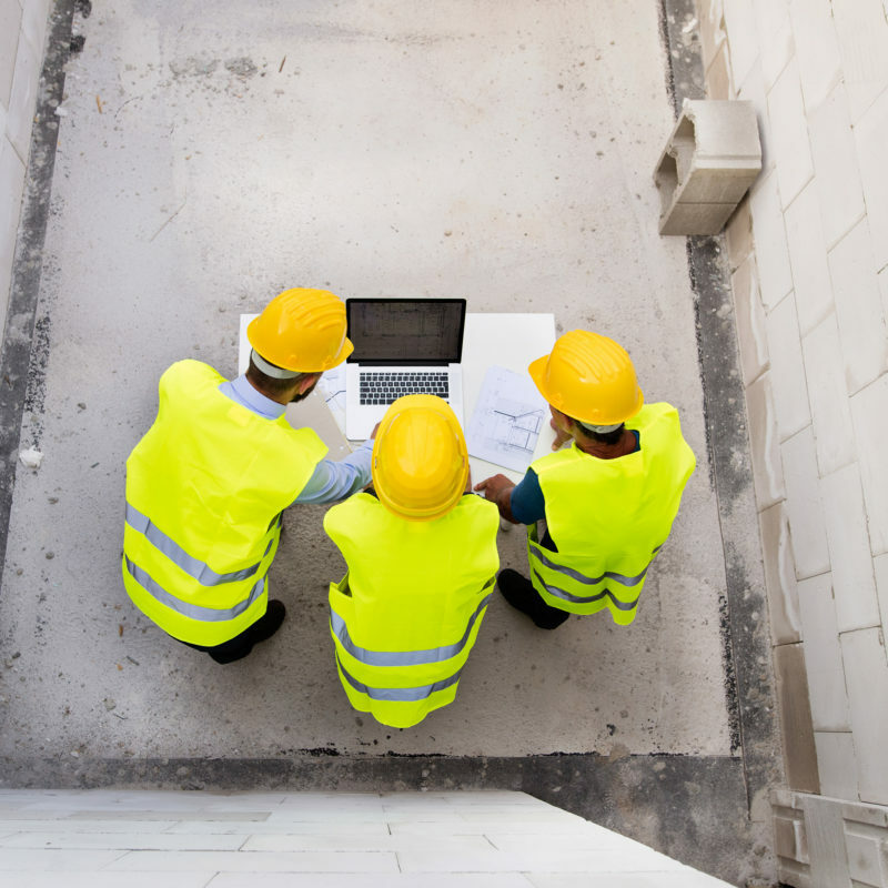 Architect, civil engineer and worker looking at plans and blueprints, discussing issues at the construction site.